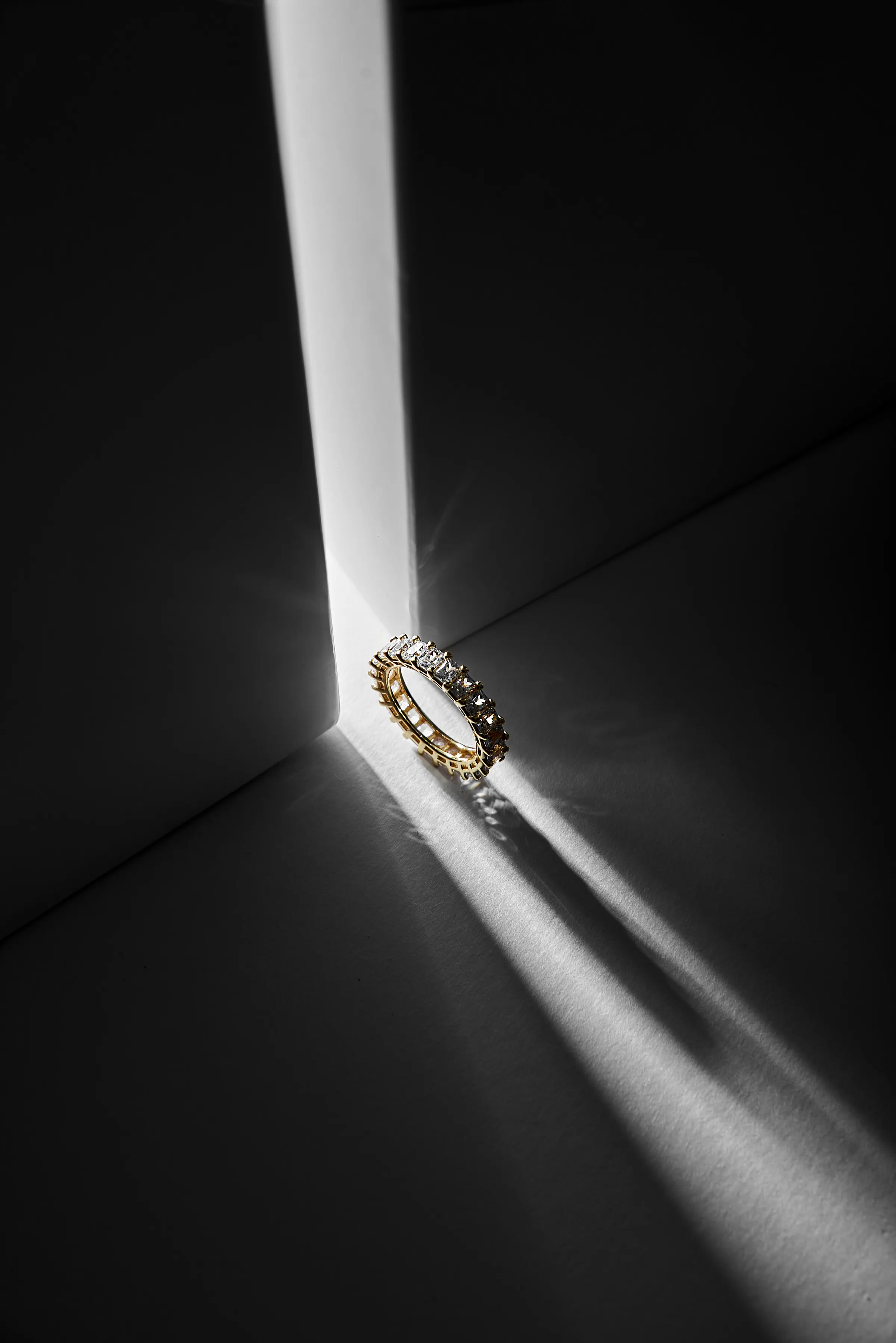 Diamantring in einer grafischen Schwarz-Gold-Lichtinszenierung