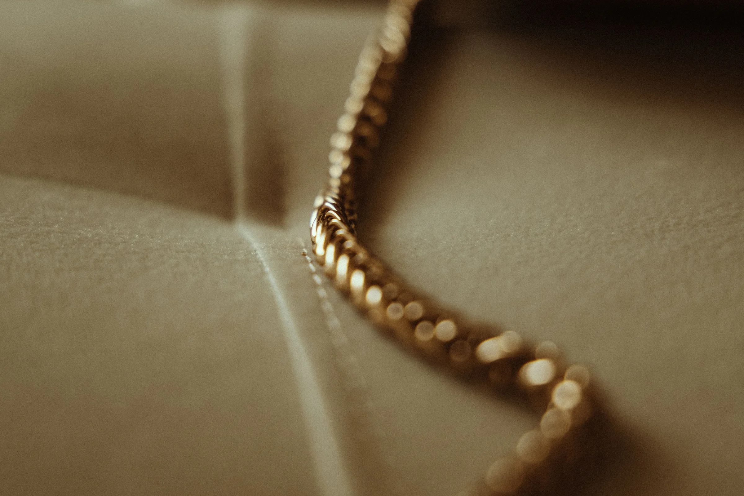 Goldkette in warmem Licht auf weich drapiertem Satin